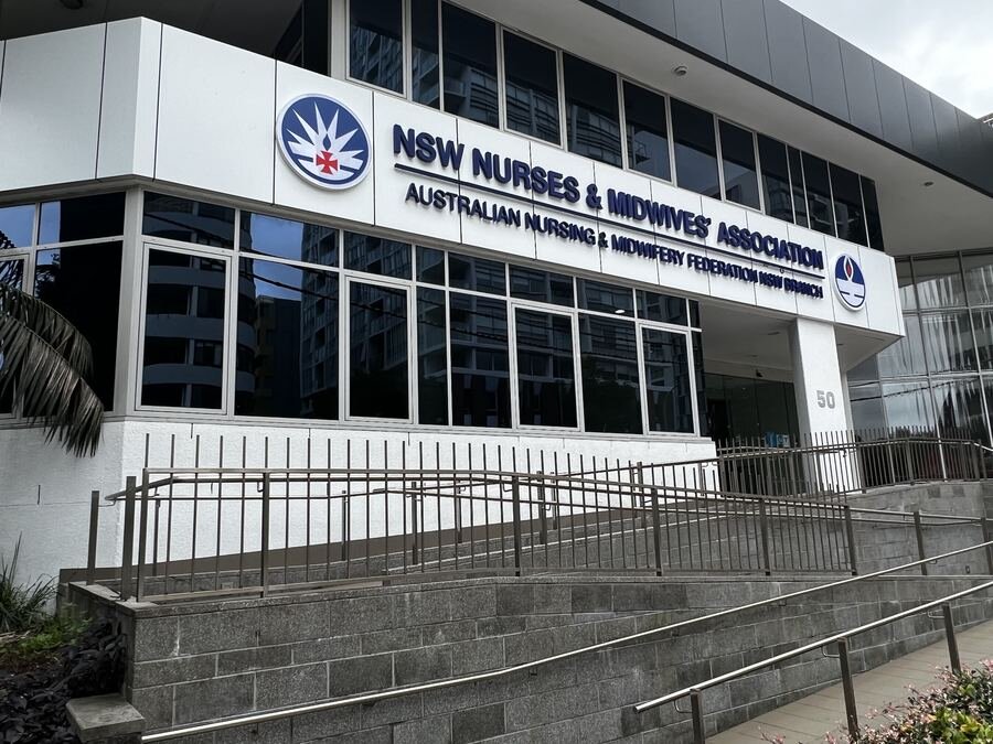 Blue backlit channel letters on modern white glass building for healthcare association