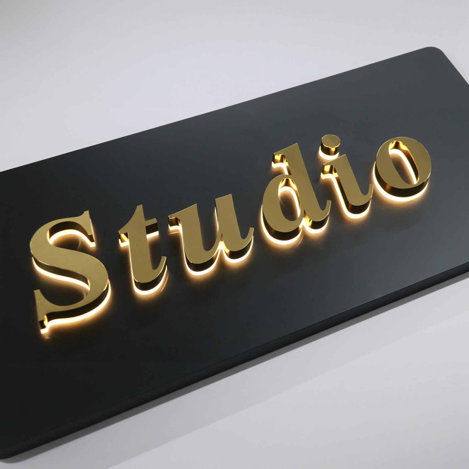 Premium gold backlit custom channel letters with mirror finish and clear acrylic face, factory product shot