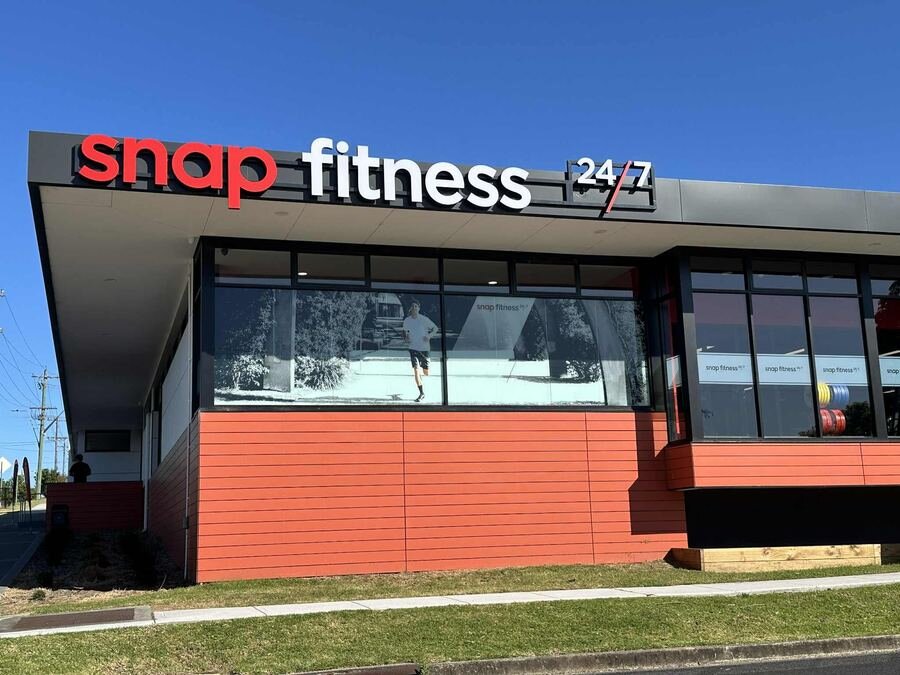 Snap Fitness 24/7 red and white front-lit channel letters on orange exterior wall