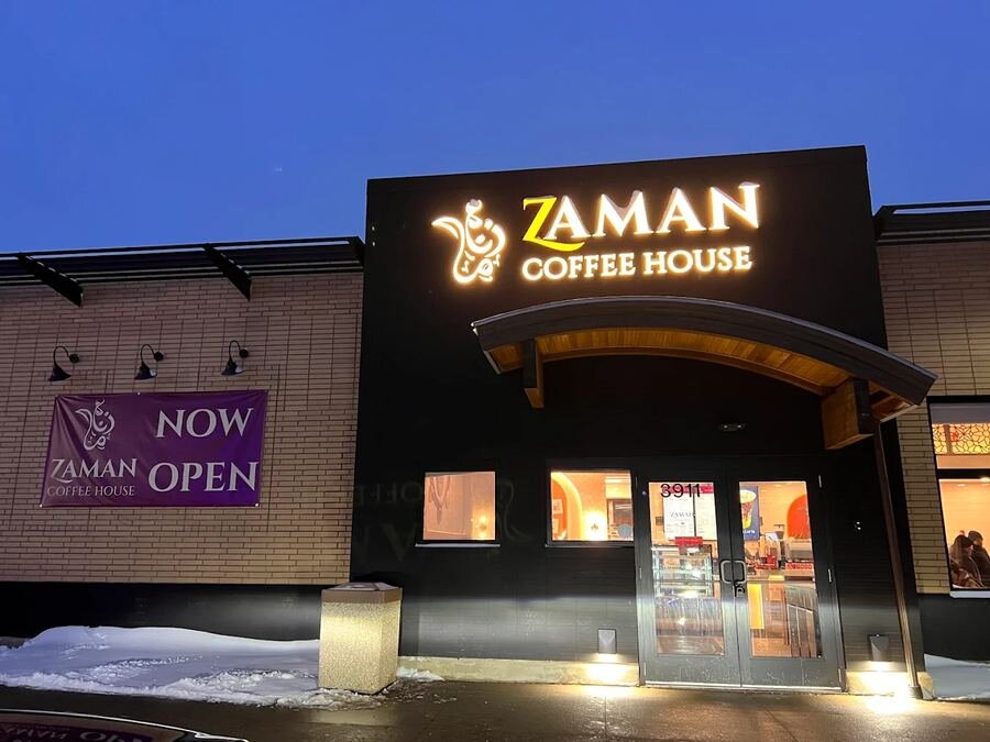 Zaman Coffee House warm yellow front-lit channel letters on black wall in snowy winter